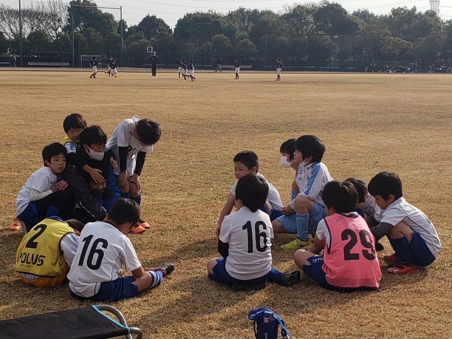 サッカー場で子どもたちが指導者を囲む、みずのスポーツクラブの活動風景